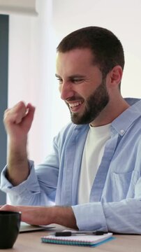 Excited professional celebrating success while working on a laptop computer in a bright office space