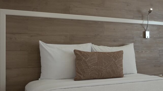 Close up of a beautifully made bed featuring clean and elegantly arranged pillows
