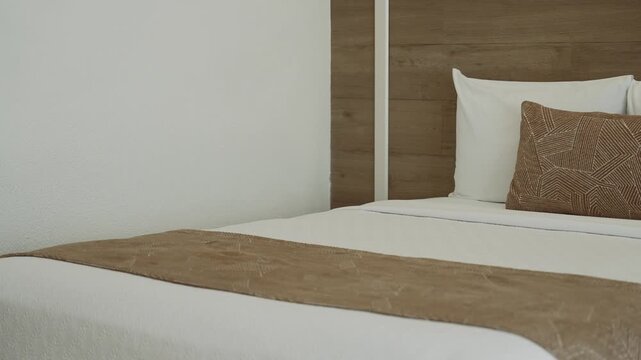 Close up of a beautifully made bed featuring clean and elegantly arranged pillows
