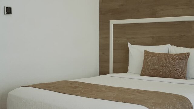 Close up of a beautifully made bed featuring clean and elegantly arranged pillows
