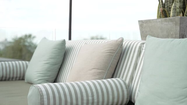 Close up of a stylish sofa featuring a collection of neat blue-gray striped and solid cushions
