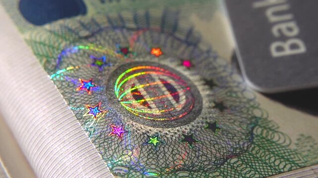 A close-up of the illuminated holographic emblem of the EU Schengen visa. The iridescent multicolor security hologram of the Schengen visa of the European Union countries. 4k slow motion video 60 fps.