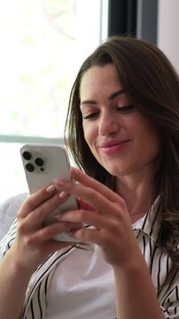 Happy young woman using her mobile phone for communication and social media browsing at home