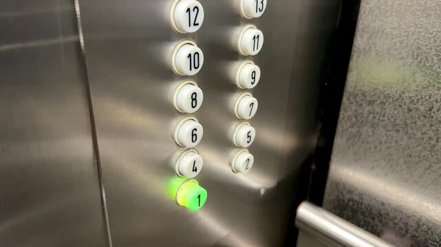 Close-up elevator panel with illuminated buttons, stainless steel surface, numeric floor indicators cycling, green and red LEDs