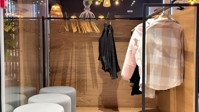 Empty restaurant wardrobe with hanging coats. Filming of premises captures quiet cloakroom corner with round ottomans, wooden