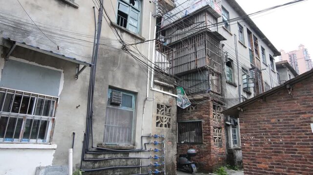 Aged residential buildings with security bars and exposed wiring in Yizhou, Guangxi China. Urban decay and old neighbourhood. Concept of housing, proverty issue, redevelopment, and social contrast