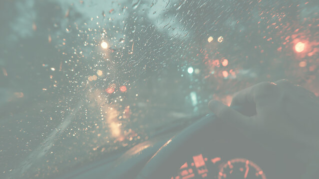 夜の雨の車内で水滴のついたフロントガラス越しの街の光とハンドルを握る手