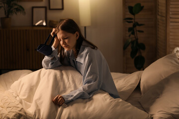 Fototapeta premium Young woman suffering from headache in bed at night