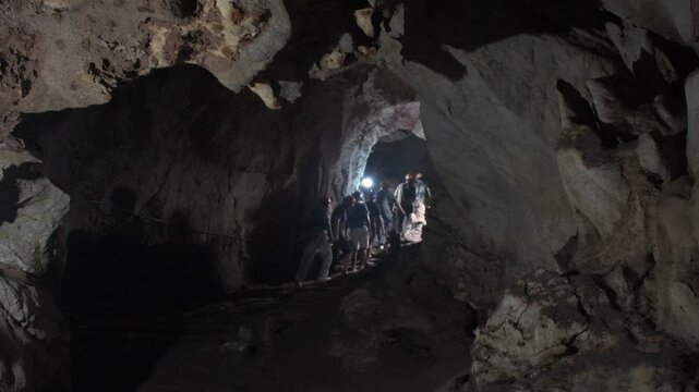 exploring a broad limestone passage inside khao wang thong cave in southern thailand, with headlamps illuminating the ancient underground karst landscape