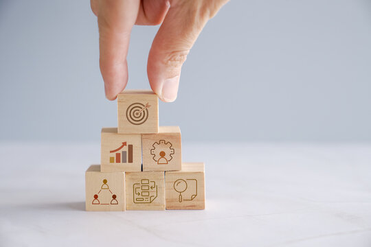 Hands holding wooden blocks with business icons, business strategy management, set goal and target, collaboration business concept
