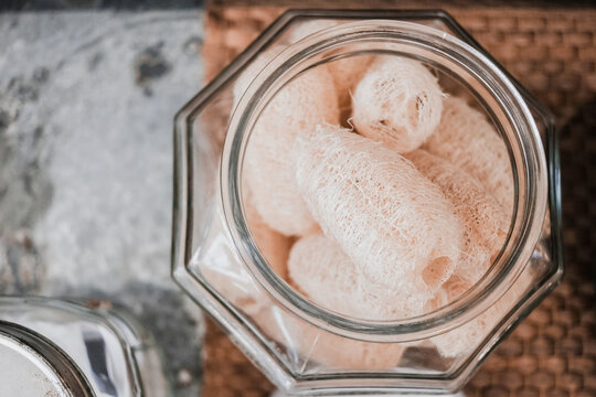 loofah, sponge, natural, eco-friendly, zero waste, sustainable, organic sponges stored in a clear glass jar for a plastic-free bathroom and healthy skin care routine at home.