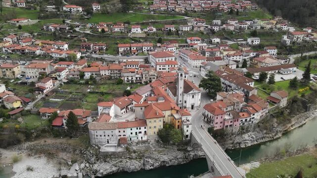 Aerial view of the historic town of Kanal ob Soci with its stone bridge over the emerald Soca river, surrounded by lush hills and traditional rooftops in Kanal ob Soci, Nova Gorica, Slovenia.