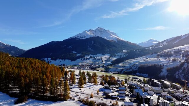 Aerial view of the village of Savognin nestled in the snowy mountains of the Surses valley with pine forests and alpine slopes in Surses, Grisons, Switzerland.