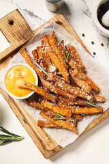 Naklejka premium Wooden board with tasty cooked sweet potato, grated Parmesan cheese, rosemary and bowl of sauce on marble background