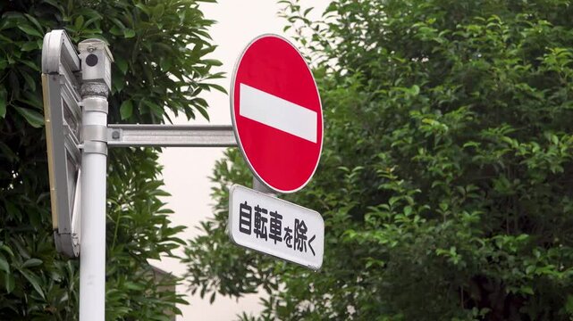 Centered no entry road sign with bicycle exception in light rain on a Tokyo morning
