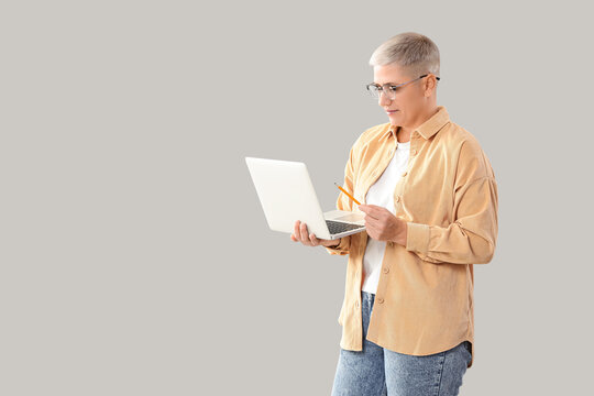 Female programmer working with laptop on light background