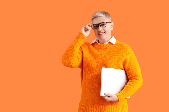Female programmer with laptop on orange background