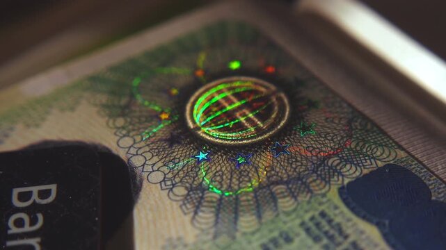 A close-up of the illuminated holographic emblem of the EU Schengen visa. The iridescent multicolor security hologram of the Schengen visa of the European Union countries. 4k slow motion video
