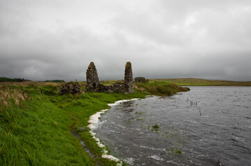 Historic stone ruins at Finlaggan on Eilean Mòr, Islay, Scotland beside a windswept loch © Jaime