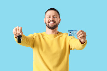 Fototapeta premium Young man with driving license and car key on blue background