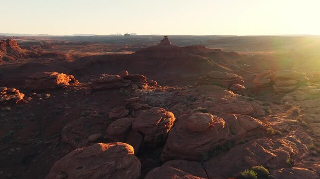 Aerial view of rugged red rock formations and vast desert terrain illuminated by warm golden hour light in Moab, Utah, United States.