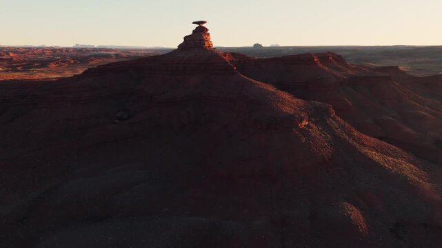 Aerial view of the iconic Mexican Hat rock formation rising above the desert landscape during golden hour in Moab, Utah, United States.