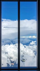 Obraz premium Framed view of blue sky and billowing white clouds seen through a glass window