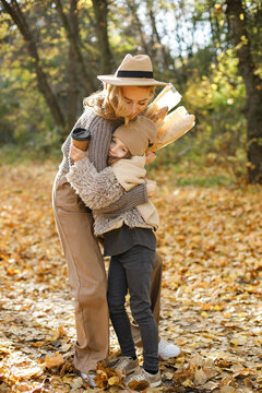 Fashionable young mother with a little daughter in autumn park