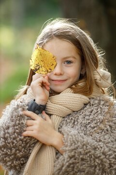Portrait of a little girl in autumn park posing for a photo