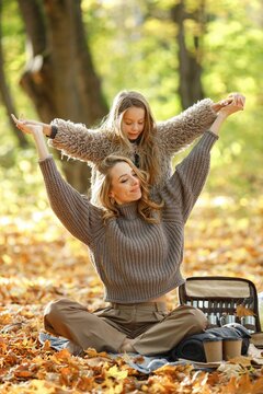 Fashionable young mother with a little daughter in autumn park