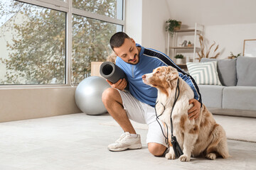 Obraz premium Young man and Australian Shepherd dog with sports equipment at home
