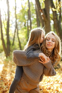 Fashionable young mother with a little daughter in autumn park