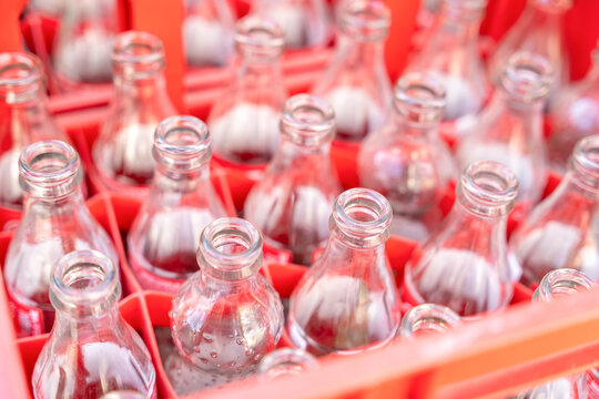 Empty clear glass bottle arranged in a red plastic crate viewed from above, recycling and beverage industry concept
