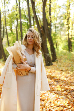 Portrait of a curly woman with baguettes outdoors in autumn park