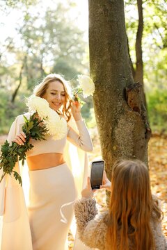 Portrait of a curly woman with flowers and her daughter outdoors in park
