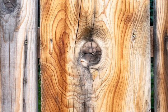 Close-up of natural wooden plank with a prominent knot and grain texture, rustic wood background for design and craft