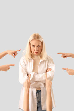 People pointing at mature woman on light background. Accusation concept