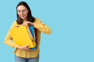 Obraz premium Young businesswoman with document folders on blue background
