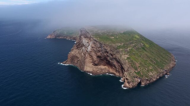 Aerial view of the Ilheus das Cabras volcanic islets rising from the Atlantic Ocean with steep cliffs and green grassy slopes in the Azores, Portugal.