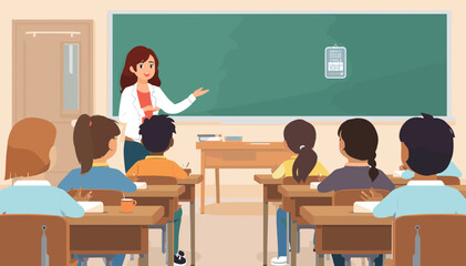 A female teacher stands at the front of a classroom, pointing at a blackboard while teaching a group of young, diverse students sitting at their desks. © evans
