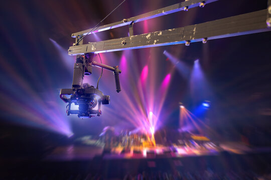 Film production, overhead camera crane captures live concert stage with dynamic lighting and motion blur during performance recording