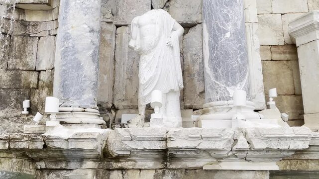 Tilt Up of Water Flowing Past Ancient Headless Roman Statue at Antonine Nymphaeum in Sagalassos Turkey