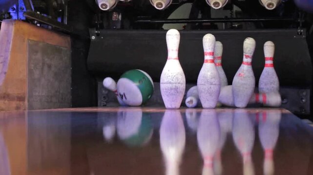 Playing bowling game with competitive athlete throwing ball down the lane for a perfect strike in 4K Ultra HD footage.

