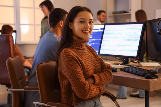 Female Asian programmer working with team at office in evening