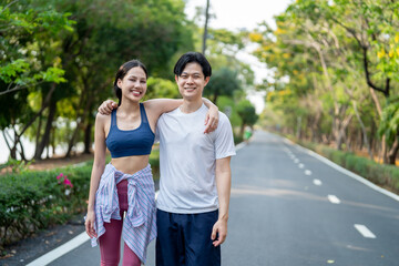 Fototapeta premium Asian young couple doing morning exercise together outdoors in garden.