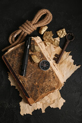 Travel equipment with old manuscripts and golden nuggets on black background © Pixel-Shot