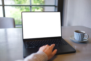 Fototapeta premium Mockup image of a woman working on laptop computer with blank white desktop screen