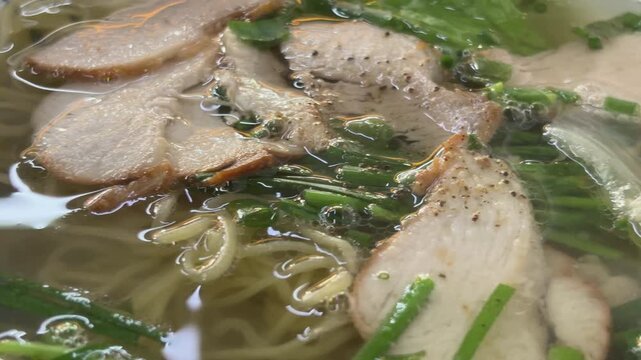 Close-up of a delicious bowl of traditional Chinese noodle soup with BBQ pork (Char Siu) and scallions