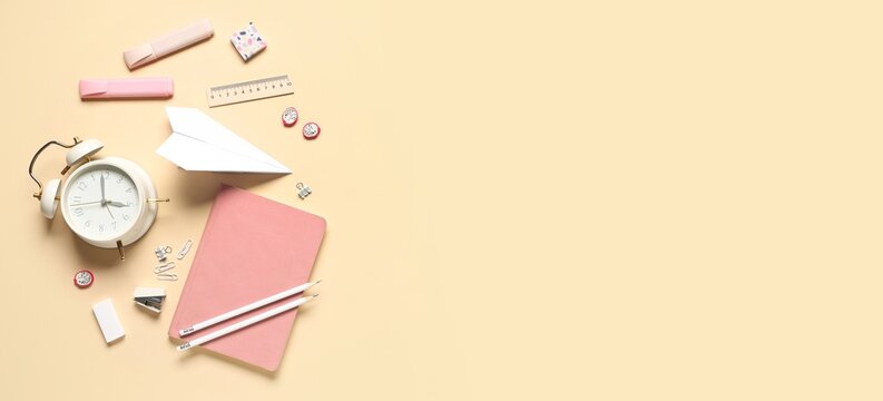 Flat lay of pink notebook and office supplies on beige background