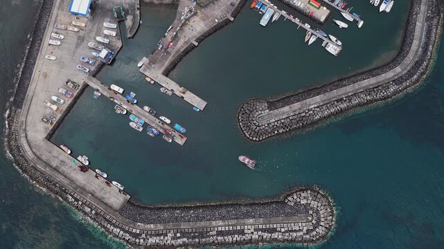 Aerial view of the marina in Sao Pedro with docked boats and breakwaters in Sao Pedro, Acores, Portugal.